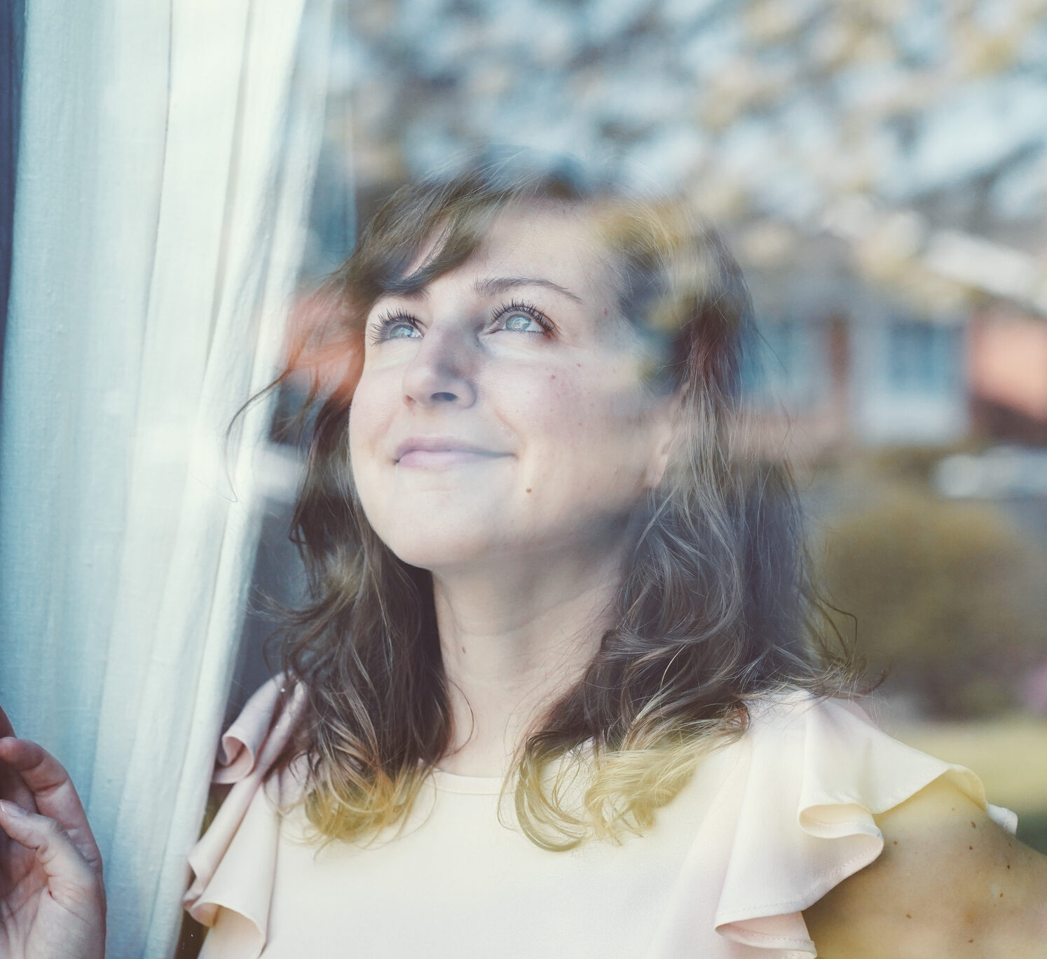 Young woman looking outside the window with hope during covid 19 lockdown spring time oxford