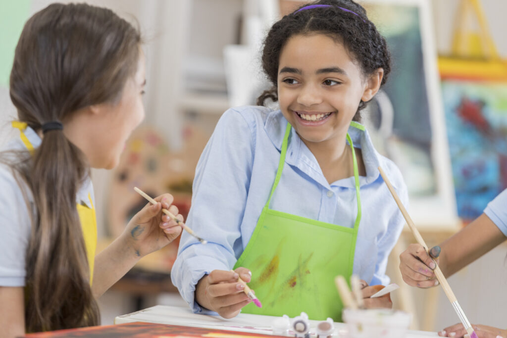 Beautiful african american preteen girls paint in art class